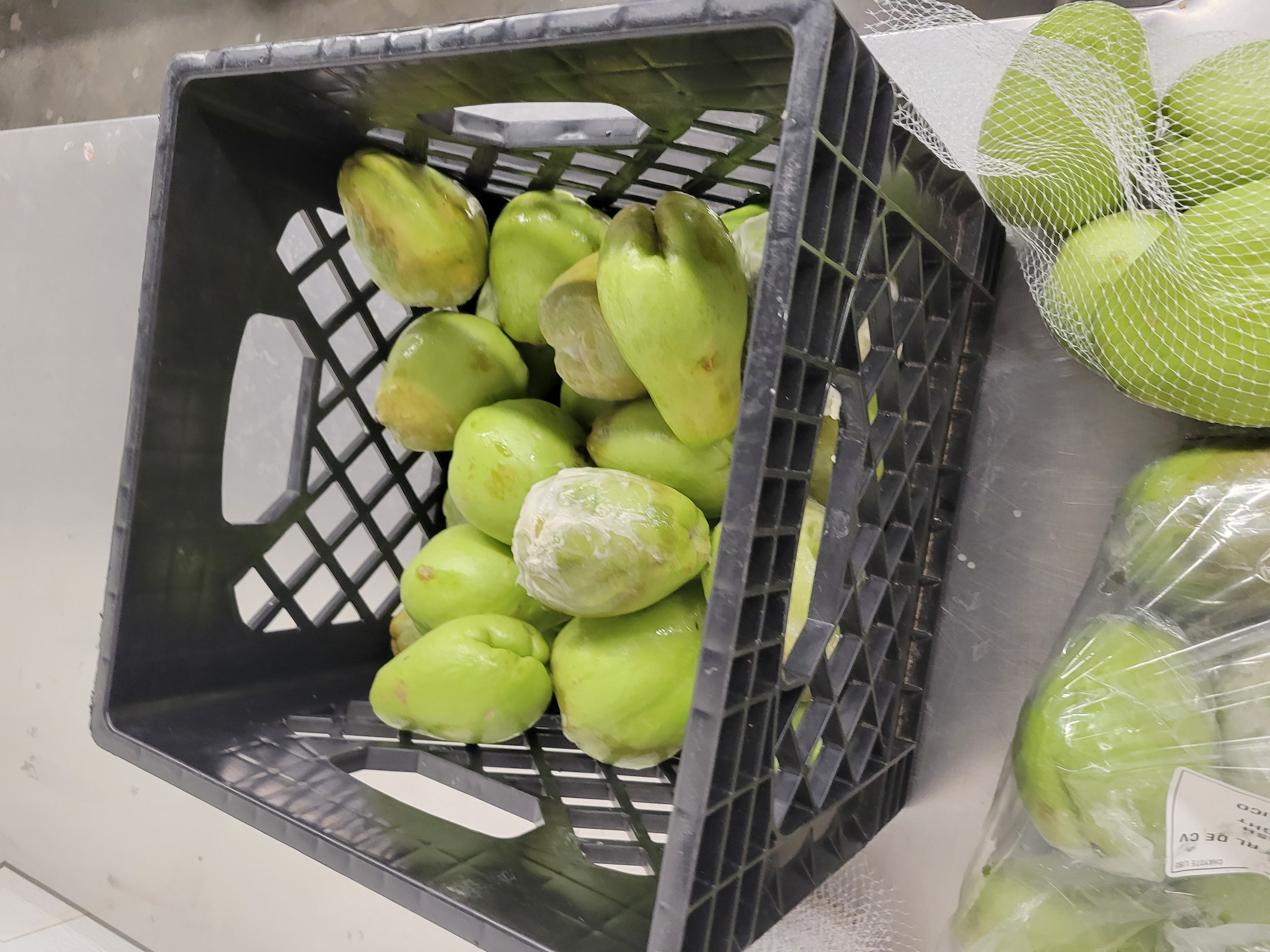 Plastic bag of pears, mesh bag of good pears, and crate of bad pears near each other.